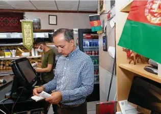  ?? Yi-Chin Lee / Staff photograph­er ?? Omer Yousafzai goes through receipts while his employee, Hazrat Nabi Safi, prepares an order for guests at the Afghan Village, Yousafzai’s restaurant on Hillcroft.