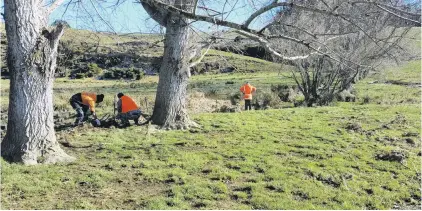  ?? PHOTO:SUPPLIED BY DEPARTMENT OF CORRECTION­S ?? Helping hands . . . Offenders on community work carry out repairs to a farm fence after flooding near Balclutha last July.