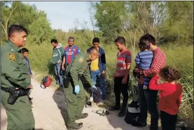  ?? MOLLY HENNESSY-FISKE/LOS ANGELES TIMES ?? Rio Grande Valley Acting Sector Chief Raul Ortiz, left, observes as agents process a group of 10 Honduran immigrants, including two children and a baby in a blue striped onesie trying to cross the border near Anzalduas Park in Mission, Texas.