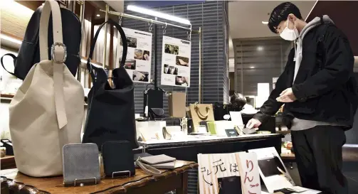  ?? The Yomiuri Shimbun ?? A customer looks at products made of apple leather at the Yurakucho Marui department store in Chiyoda Ward, Tokyo.