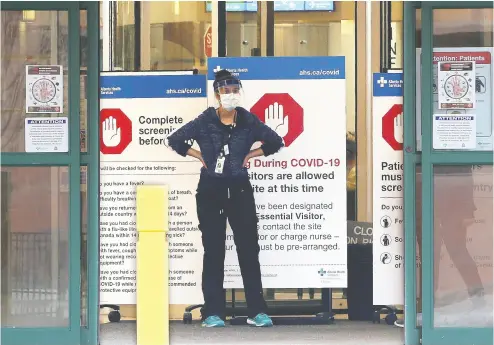  ?? GAVIN YOUNG / POSTMEDIA NEWS ?? Peter Lougheed Centre staff in Calgary, Alta., wait to screen “essential visitors” at the hospital on Tuesday.