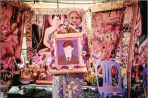  ?? JADE SACKER ?? Khouy Moek holds a portrait of her late husband Ouy Sok, who was beheaded last week in Kampot province by villagers who suspected him of sorcery.