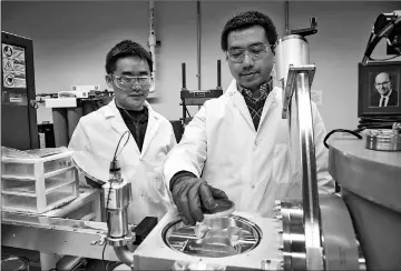  ??  ?? Research associate Xue Sichuang (left) and doctoral student Qiang Li, prepare a sample for research to create super-strong aluminium alloys. — Purdue University photo by Marshall Farthing