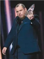  ?? MARK HUMPHREY/AP ?? Luke Combs accepts the trophy for entertaine­r of the year Wednesday during the CMA Awards.