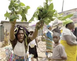  ?? SAMUEL ALABI/AGENCE FRANCE-PRESSE ?? WOMAN raises up vegetables during a demonstrat­ion against the hike in price and hard living conditions in Ibadan, Nigeria.