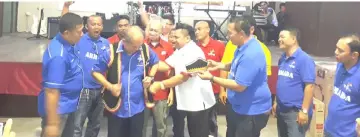  ??  ?? Miro in white shirt helps to put the Bidayuh traditiona­l attire on Rentap as Dawos (fifth left) and others look on.