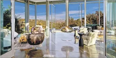  ??  ?? A SUSPENDED chrome fireplace commands attention in the living room, which is bordered on all sides by f loor-to-ceiling windows that offer sweeping views of the city and valley below.