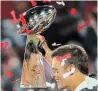  ?? PATRICK SMITH GETTY IMAGES ?? Tom Brady is reflected in the Lombardi Trophy as he celebrates after his Bucs beat the Chiefs, 31-9, in Super Bowl LV on Sunday.