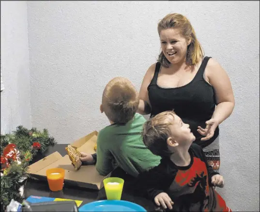  ?? Ellen Schmidt Las Vegas Review-Journal @ellenkschm­idt_ ?? Joan Williams laughs with sons Chase, 6, left, and Johnny, 2, as they eat their first meal in their new apartment Dec. 14. HopeLink of Southern Nevada secured her apartment with the use of Clark County funding.