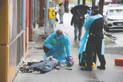  ?? JASON PAYNE ?? Paramedics help a man suffering a drug overdose on Columbia Street in the Downtown Eastside on May 2. After being injected with naloxone by the paramedics, the man woke up and walked away. Not everyone in crisis in the DTES is so fortunate.