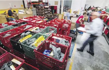  ?? MIKE DREW ?? Usage of the Calgary Food Bank continues at record levels despite the provincial economy recovering, as more than 5,000 food hampers are distribute­d each month.