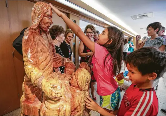  ?? Photos by Steve Gonzales / Staff photograph­er ?? Members of the First Christian Church get an up-close look at the “Jesus and the Little Children” sculpture during a recent dedication ceremony.