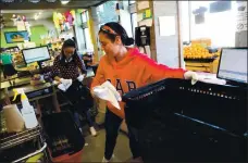  ?? ARIC CRABB — STAFF ARCHIVES ?? Employees Angelica Villar, center, and Elizabeth Rodriguez, right, disinfect shopping baskets at Mi Tierra Foods on April 1, 2020, in Berkeley.