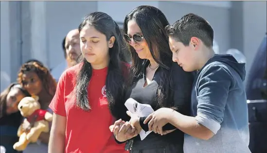  ?? Carolyn Cole Los Angeles Times ?? A STUDENT at Marjory Stoneman Douglas High School, Antonina Messina, left, is joined by her mother and brother at a vigil Thursday for the shooting victims.