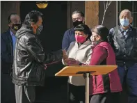  ??  ?? Santo Domingo Pueblo Gov. Sidelio Tenorio hands the key of a rebuilt adobe home to Diane Garcia on Tuesday morning during an event to celebrate an initiative to restore and rebuild homes that were severely damaged by hail and floods.