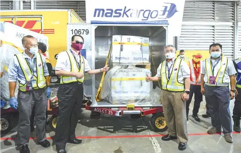  ?? - Bernama photo ?? Health Minister Datuk Seri Dr Adham Baba (second right) with Health Director-General Tan Sri Dr Noor Hisham Abdullah (second left) showing boxes containing the Pfizer-BioNTech Covid-19 vaccine soon after its arrival at the Kuala Lumpur Internatio­nal Airport yesterday.