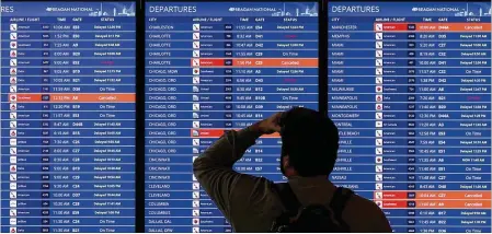  ?? ALEX WONG/GETTY IMAGES/TNS ?? A traveler looks at a flight informatio­n board at Ronald Reagan Washington National Airport in January in Arlington, Virginia. Plans to increase air traffic at Reagan National could increase flight delays by as much as one-third, according to an FAA analysis.