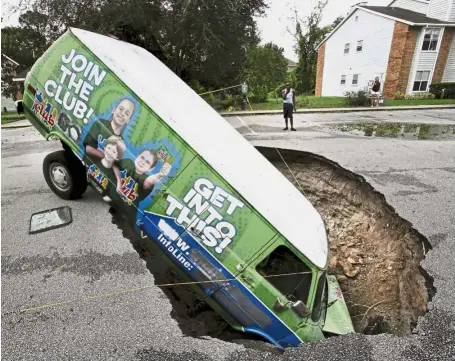  ??  ?? Staying in: A van remains in a sinkhole that opened up at the Astor Park apartment complex in Winter Springs during Hurricane Irma’s passing through central Florida. — AP