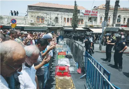  ?? (Marc Israel Sellem/The Jerusalem Post) ?? MUSLIMS PRAY in east Jerusalem on Friday, as police keep between them and the Damascus Gate entrance to the Old City.