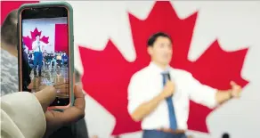  ?? JONATHAN HAYWARD/THE CANADIAN PRESS ?? A woman films Prime Minister Justin Trudeau on her smartphone as he addresses a town-hall meeting in Saskatoon on Thursday.