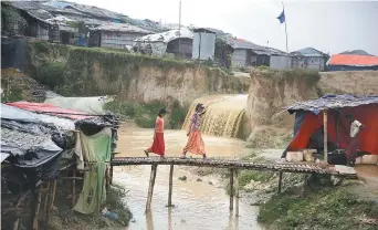  ??  ?? Deux jeunes réfugiées traversent un pont de fortune, mardi, au camp de Kutupalong, au Bangladesh. - Associated press: Altaf Qadri