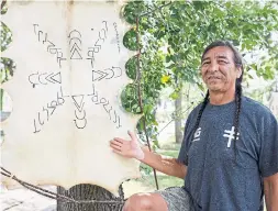  ??  ?? Nehiyaw language instructor Reuben Quinn with a spirit marker in Edmonton. He says Indigenous languages were decimated by bans at residentia­l schools.