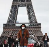  ?? Reuters ?? A woman wearing a mask walks in front of the Eiffel Tower, as the tourist industry in France has been badly affected by the coronaviru­s crisis.