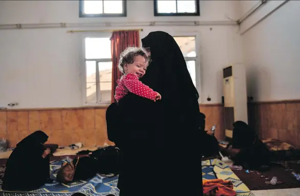  ?? BULENT KILIC/AFP/GETTY IMAGES ?? The wife of a suspected member of the Islamic State group holds her child as she waits on the western front line to be questioned after fleeing Raqa this fall. Women have been fleeing ISIL for home but a disturbing number have embraced the group’s ideology and remain committed to its goals, officials tracking the returnees say.