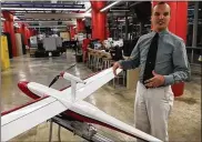  ?? THOMAS GNAU / STAFF ?? Andrew Shepherd, who heads Sinclair Community College’s unmanned aerial vehicles program, stands next to a version of Unmanned Solutions Technology’s Pelican II fixed-wing UAV in July.