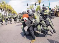  ?? JAE C. HONG/ASSOCIATED PRESS ?? Orange County sheriff’s deputies take a protester into custody outside the Anaheim Convention Center on Wednesday, where GOP presidenti­al candidate Donald Trump spoke.