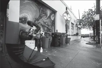  ?? FRANCINE ORR/LOS ANGELES TIMES ?? A homeless woman goes through the recycle bins in front of the warehouse known as “Death Trap” on Dec. 8 in Oakland.