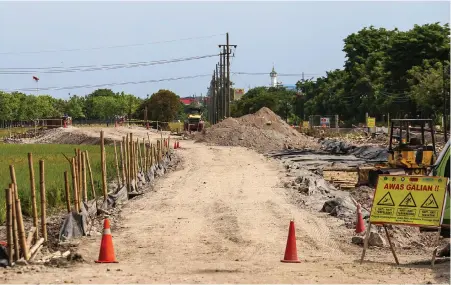  ?? DIMAS MAULANA/JAWA POS ?? HARUS DIGESER: Deretan tiang listrik di lahan frontage. Akhir tahun ini, jalur frontage sepanjang 1,6 kilometer harus rampung.