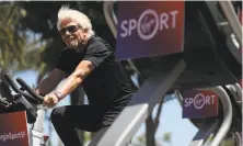  ?? Justin Sullivan / Getty Images ?? Sir Richard Branson rides an exercise bike in San Francisco in May as he announces the inaugural Virgin Sport festival. The event has been canceled because of poor air quality.