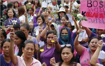  ??  ?? Protesters raise flowers during a rally to mark Internatio­nal Women’s Day Thursday in Manila, Philippine­s. Hundreds of women activists in pink and purple shirts protested against President Rodrigo Duterte. AP PHOTO/BULLIT MARQUEZ