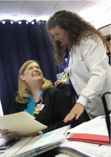  ?? (Special to The Commercial) ?? Erin Bolton, a registered nurse and director of quality and regulatory (left) at Jefferson Regional Medical Center, shares a lighter moment with Beverly Helms, performanc­e and improvemen­t coordinato­r in the hospital’s quality department. Bolton has spent the past year in the hospital’s “covid command center,” which is finally being dismantled now that infections are dropping.