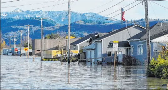  ?? Elaine Thompson The Associated Press ?? Floodwater­s inundate homes along a road Wednesday in Sumas, Wash. The soaking was fueled by an atmospheri­c river.