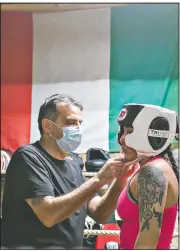  ??  ?? Steve Mazzarisi helps student Lesley Cadenas-Garcia with her headgear at the start of a sparring session. Mazzarisi founded Gladiator Boxing Club of Sterling in March 2020 and built this garage to not only help his son continue his path in boxing but to offer lessons to local youths.