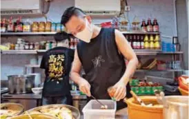  ?? ?? Xu Peinan, owner of the Chaoshan restaurant “Caogen Yedang,” and his staff prepare food in the back kitchen. — Zhou Shengjie