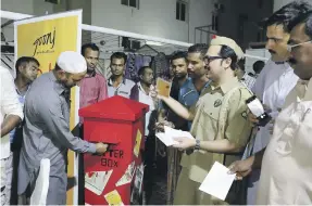  ?? Photos Pawan Singh / The National ?? Above, Faraz Waqar, a member of the theatre group Goonj, hands out paper for letters at Al Meher camp in Al Quoz, Dubai; left, the letters are posted