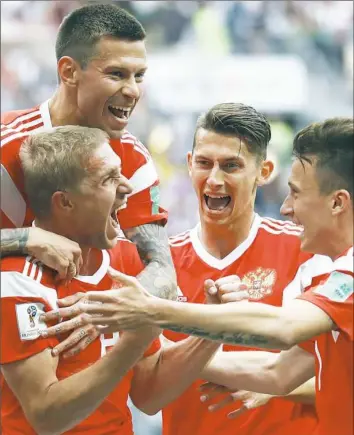  ?? Matthias Schrader/Associated Press ?? Russia’s Yuri Gazinsky, left, celebrates with teammates after scoring the first goal in a group A match Thursday between Russia and Saudi Arabia which opened the 2018 soccer World Cup at the Luzhniki stadium in Moscow.