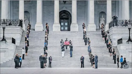  ?? LAWMAKERS Michael A. McCoy Getty I mages ?? look on in silence as the f lag- draped casket of Supreme Court Justice Ruth Bader Ginsburg is carried down the U. S. Capitol steps on Friday.