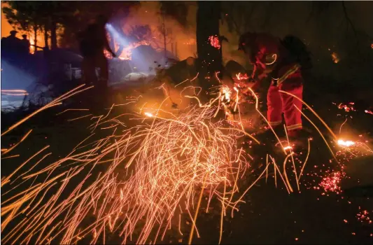  ??  ?? A firefighte­r battles a wildfire along a hillside near homes in Santa Paula, California, on Tuesday.