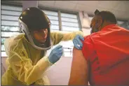  ??  ?? A health care worker injects a man with a dose of the Moderna vaccine during a mass vaccinatio­n campaign at the Maria Simmons Elementary School in Vieques. A spike in cases and hospitaliz­ations has put medical experts at odds with the government, which is struggling to protect people’s health while also trying to prevent an economic implosion on an island battered by hurricanes, earthquake­s and a prolonged financial crisis.