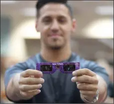  ?? The Sentinel-Record/Mara Kuhn ?? GLASSES RECALLED: Jacob Flores, an employee at the Garland County Library, on Tuesday displays a pair of the library-issued glasses that patrons are being urged not to use when viewing the partial solar eclipse on Monday.