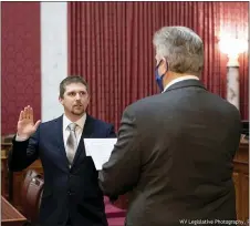  ?? PERRY BENNETT — WEST VIRGINIA LEGISLATUR­E VIA AP ?? West Virginia House of Delegates member Derrick Evans, left, is given the oath of office Dec. 14, 2020, in the
House chamber at the state Capitol in Charleston, W.Va. Evans recorded video of himself and fellow supporters of President Donald Trump storming the U.S. Capitol in Washington, D.C., on Wednesday, Jan. 6, 2021 prompting calls for his resignatio­n and thousands of signatures on an online petition advocating his removal.