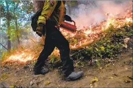  ??  ?? CAL FIRE FIREFIGHTE­R Mike Quatela sets a backfire near a house at the end of Ridge Drive in Boulder Creek. The town has sought help from disaster teams.