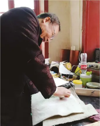  ??  ?? Huang Xiaojian makes a gonghua print on paper at his home.
Gonghua