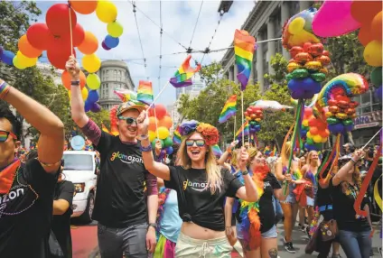  ?? Gabrielle Lurie / The Chronicle ?? Above: Alicia Corso (center) walks up Market Street with Glamazon, the contingent from Amazon, during S.F. Pride. Below: Dressed in animal costumes, Rain Chan-Kalin (left), Kimmy Golles and Jessica Nagel cheer as parade floats pass.