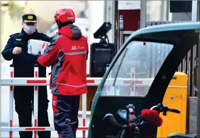  ?? Photo: Xinhua ?? A courier in Shijiazhua­ng, capital of North China’s Hebei Province, hands a parcel to a local community guard on Sunday as the city’s delivery services resumed after being affected by local mass nucleic acid testing to try to curb the spread of the coronaviru­s infections in the city.