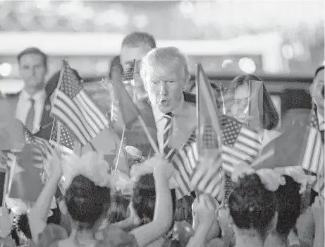  ?? Andrew Harnik / Associated Press ?? President Donald Trump greets children waving American and Vietnamese flags as he arrives Saturday at Noi Bai Internatio­nal Airport in Hanoi. Trump’s five-country trip through Asia included stops in Japan, South Korea and China. His last stop will be...